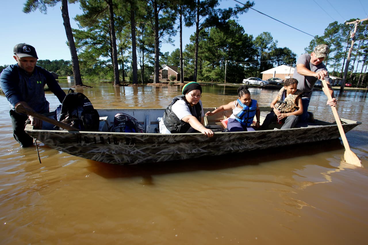 Los rescatistas Jeremy y Tommy Blue ayudan a una familia a salir de su complejo de apartamentos. (REUTERS/Chris Keane)