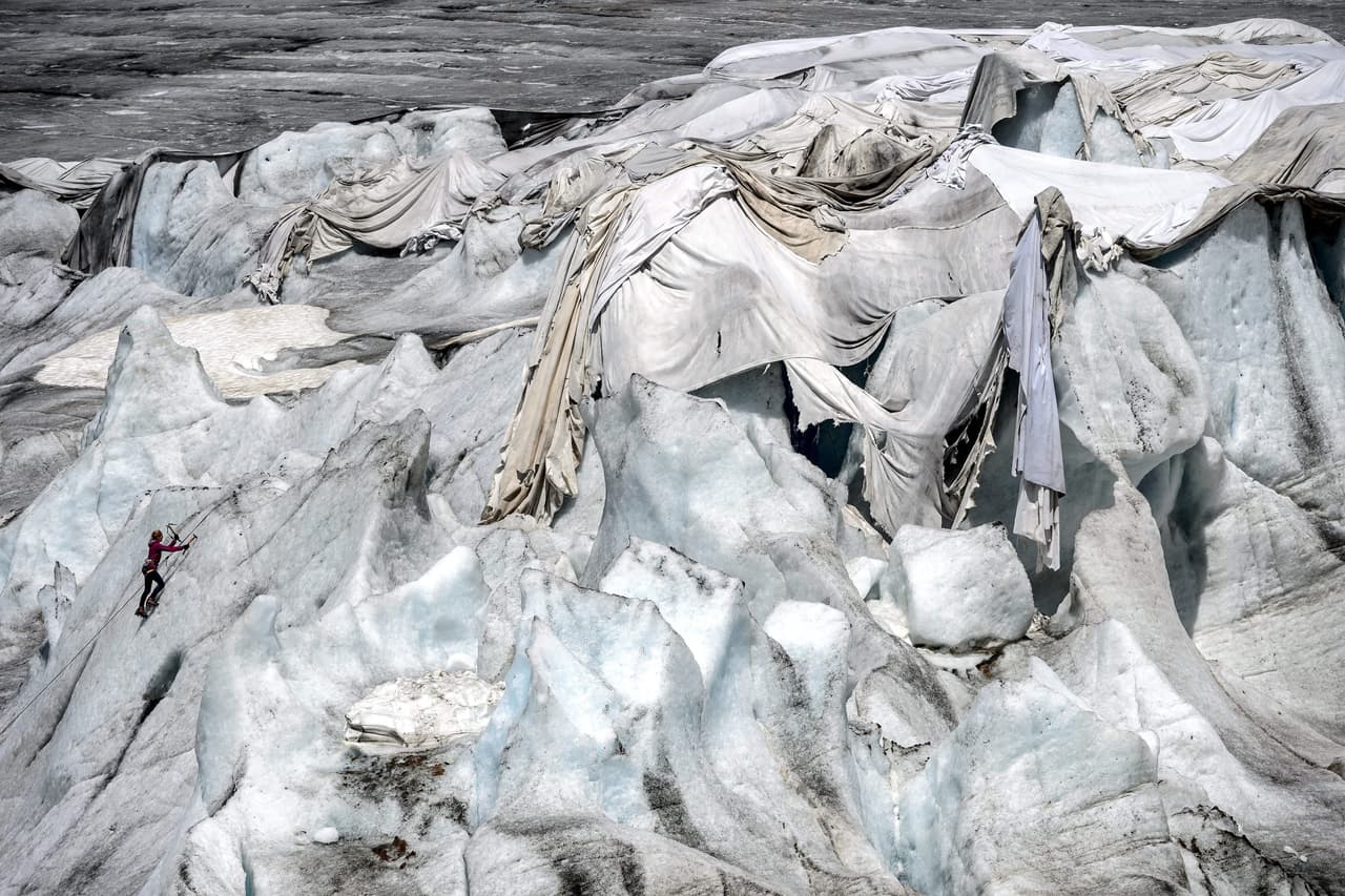 A woman practices ice climbing on July 14, 2015 next to insulating foams wrapping up the Rhone Glacier which has been shrinking under the summer sun near Gletsch. A second heat wave is forecast to hit Switzerland in the next few days. AFP PHOTO / FABRICE COFFRINI / AFP / FABRICE COFFRINI (Photo credit should read FABRICE COFFRINI/AFP/Getty Images)