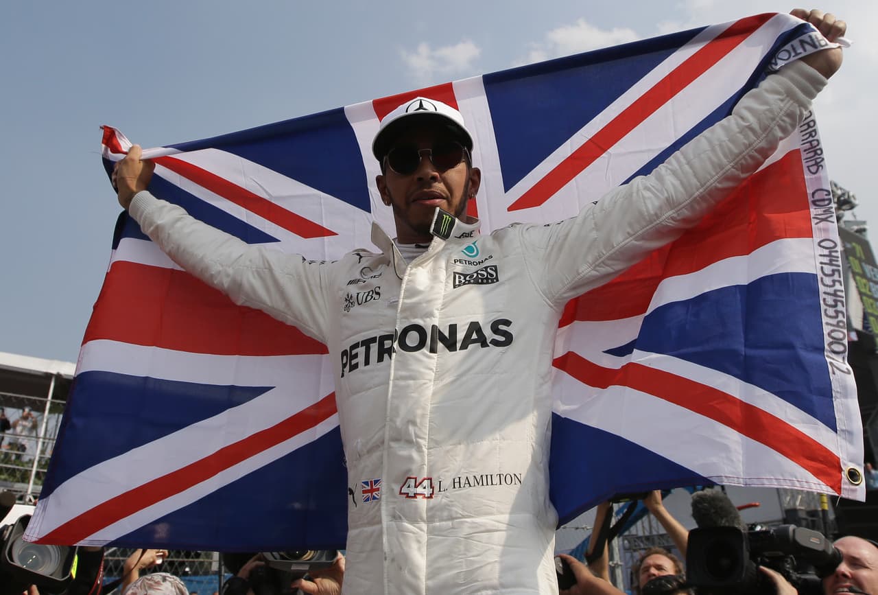 Lewis Hamilton alza la bandera británica tras ganar su cuarto título mundial de F1 con su noveno puesto en el Gram Premio de México, el domingo 29 de octubre de 2017. (AP Foto/Moises Castillo)