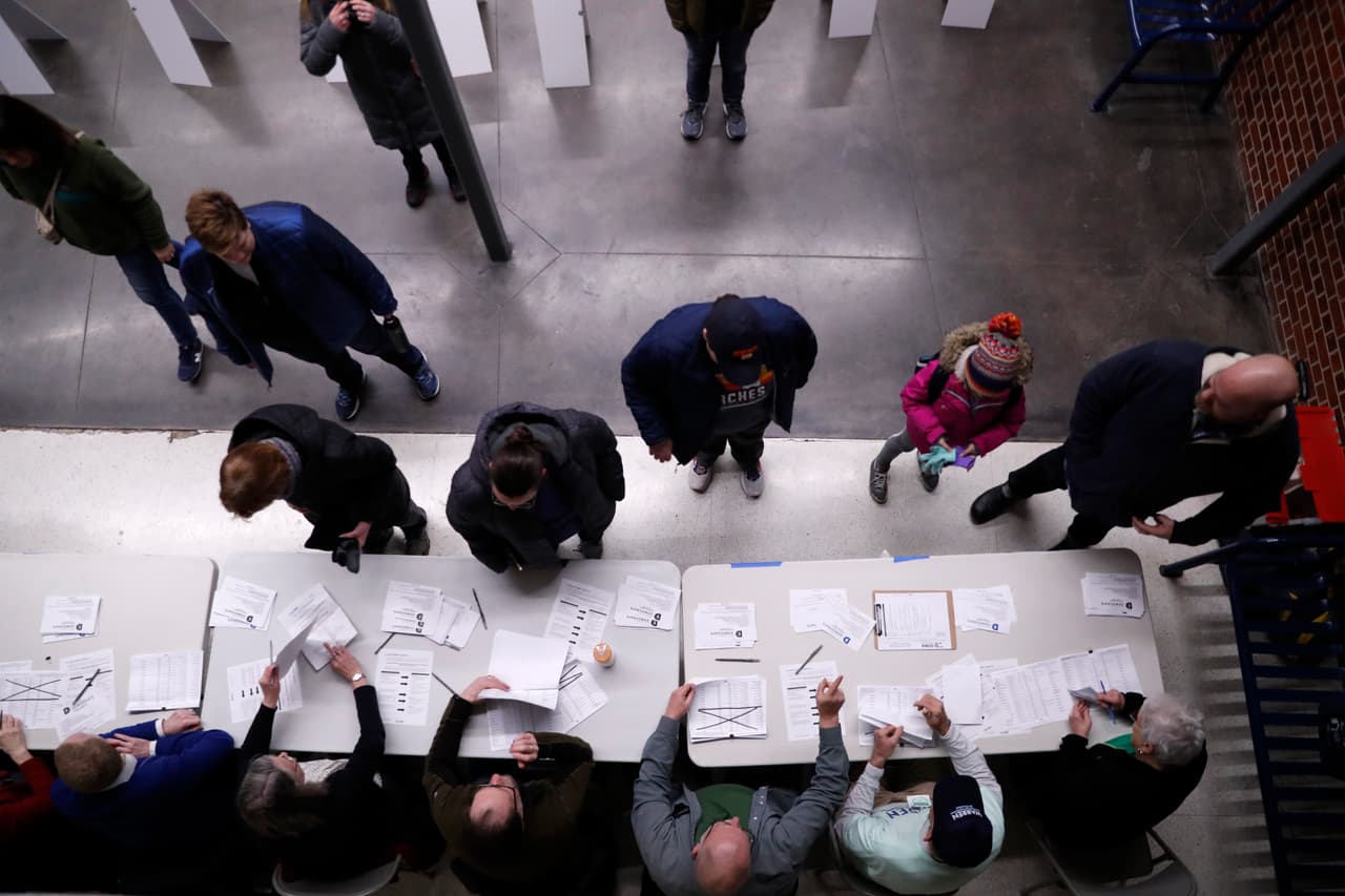 Los 'caucusgoers' (asistentes) de la asamblea electoral al momento de registrarse en la secundaria Roosevelt de Des Moines.