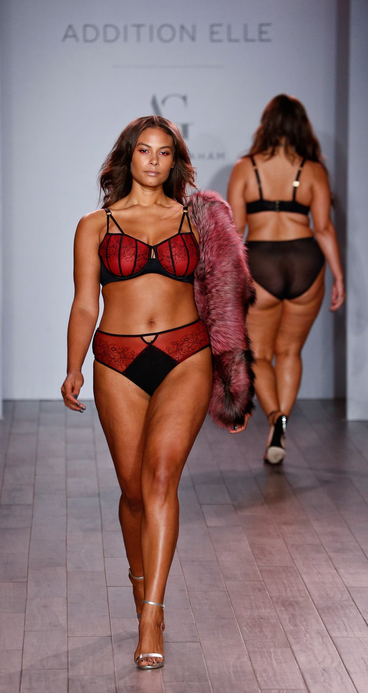 Otra foto del desfile de la firma de ropa interior de Ashley Graham para tallas grandes con un conjunto rojo y negro.