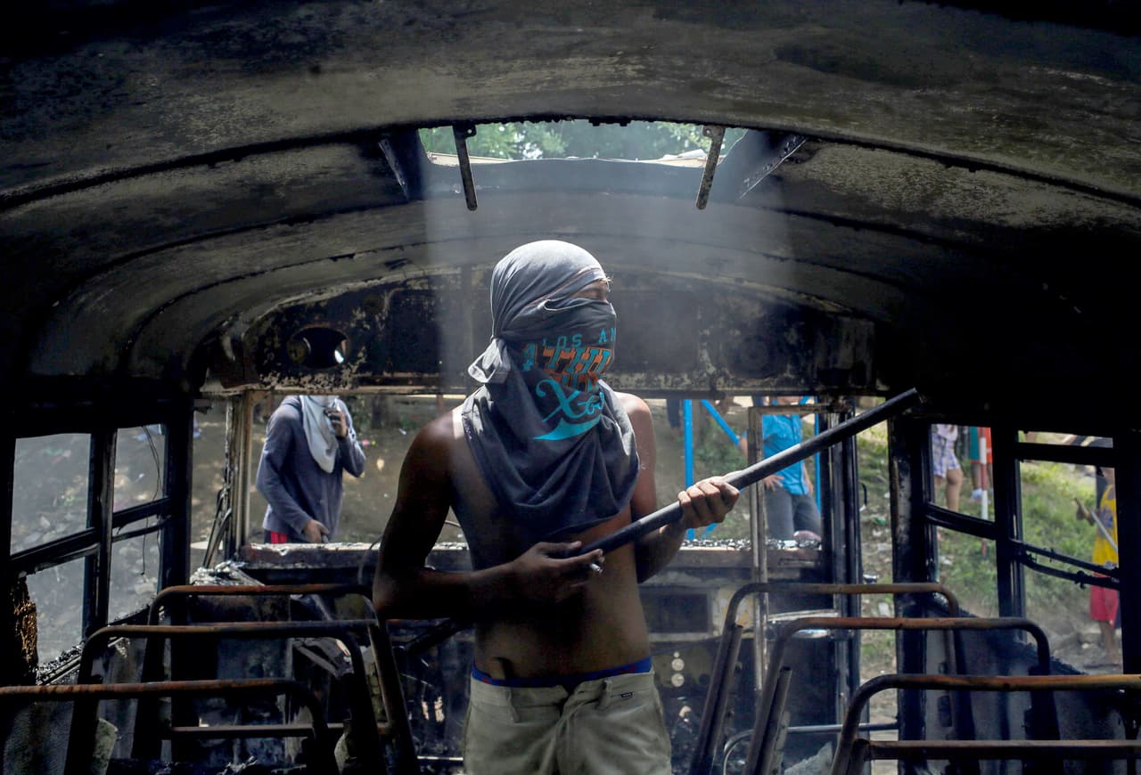 Un manifestante contra el gobierno de Daniel Ortega se mantiene atrincherado en un autobús quemado en Tipitapa, Nicaragua, el día del paro nacional convocado por los empresarios para aumentar la presión contra el gobierno de Daniel Ortega.