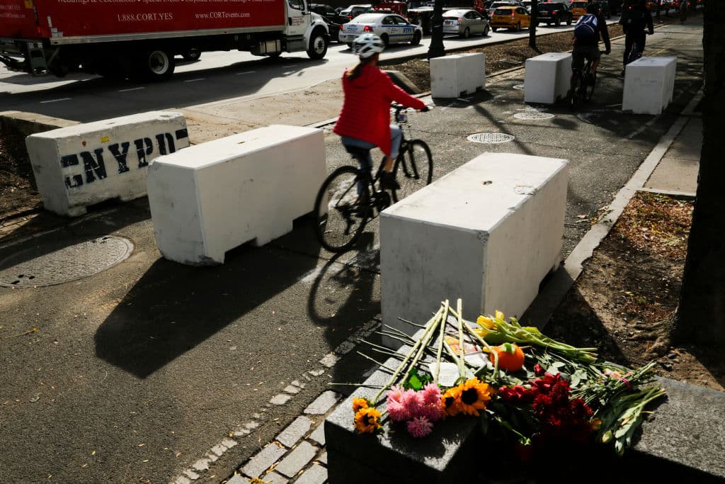 Ciclistas dejan atrás un memorial para las víctimas del ataque terrorista del martes. En esta imagen se observan las barreras que la policía de la ciudad ha instalado en distintas partes.