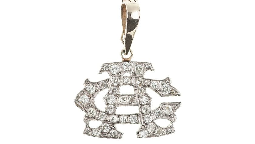 Otro de los objetos es un collar con colgante de oro de 14k con monograma "AC" 
<b>adornado con 33 diamantes, zafiro</b> y alfiler de corbata con incrustaciones de diamantes.