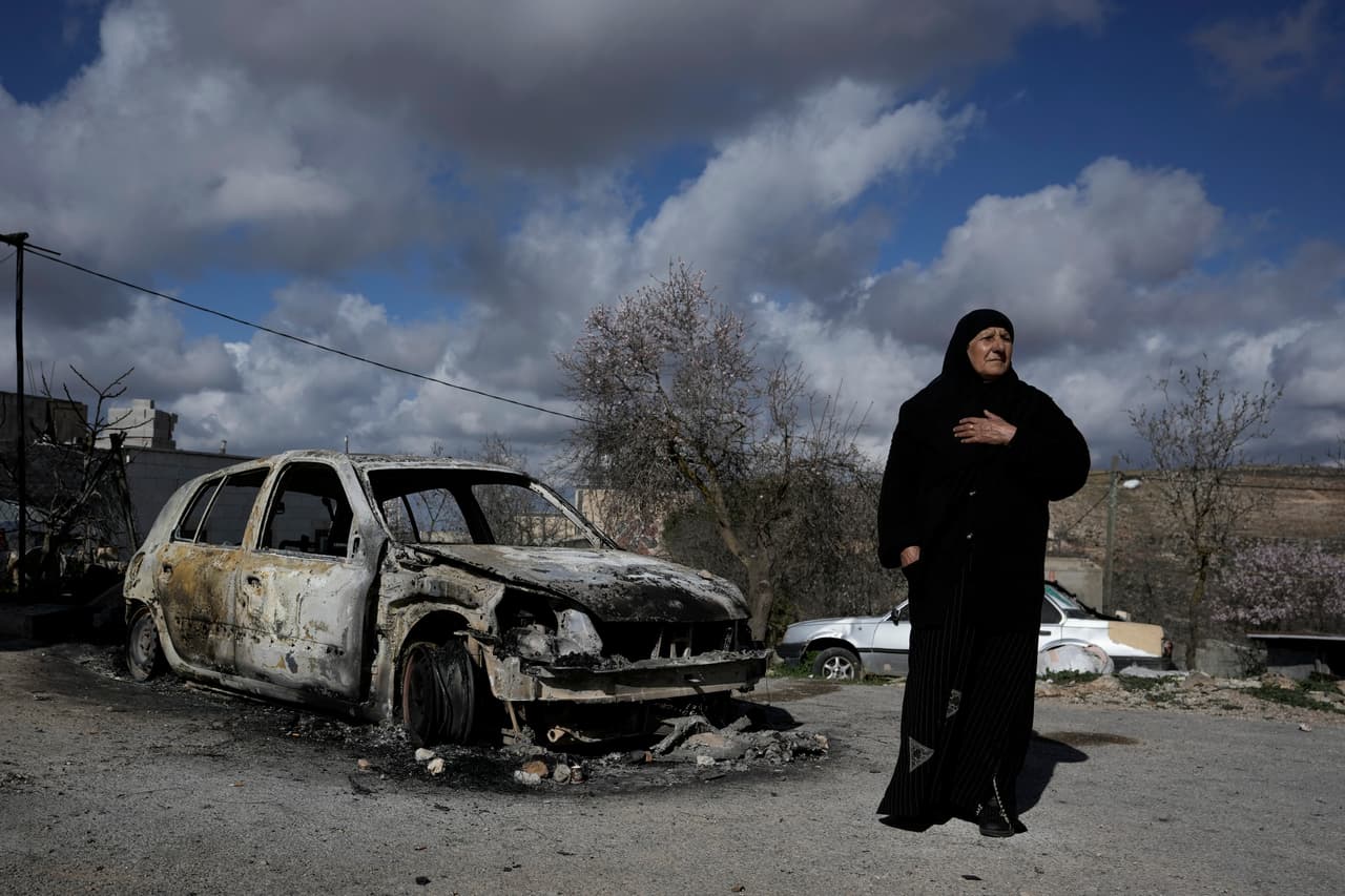 Una mujer palestina junto a un coche destruido en el pueblo de Jalud, en Cisjordania, este 30 de enero de 2023.