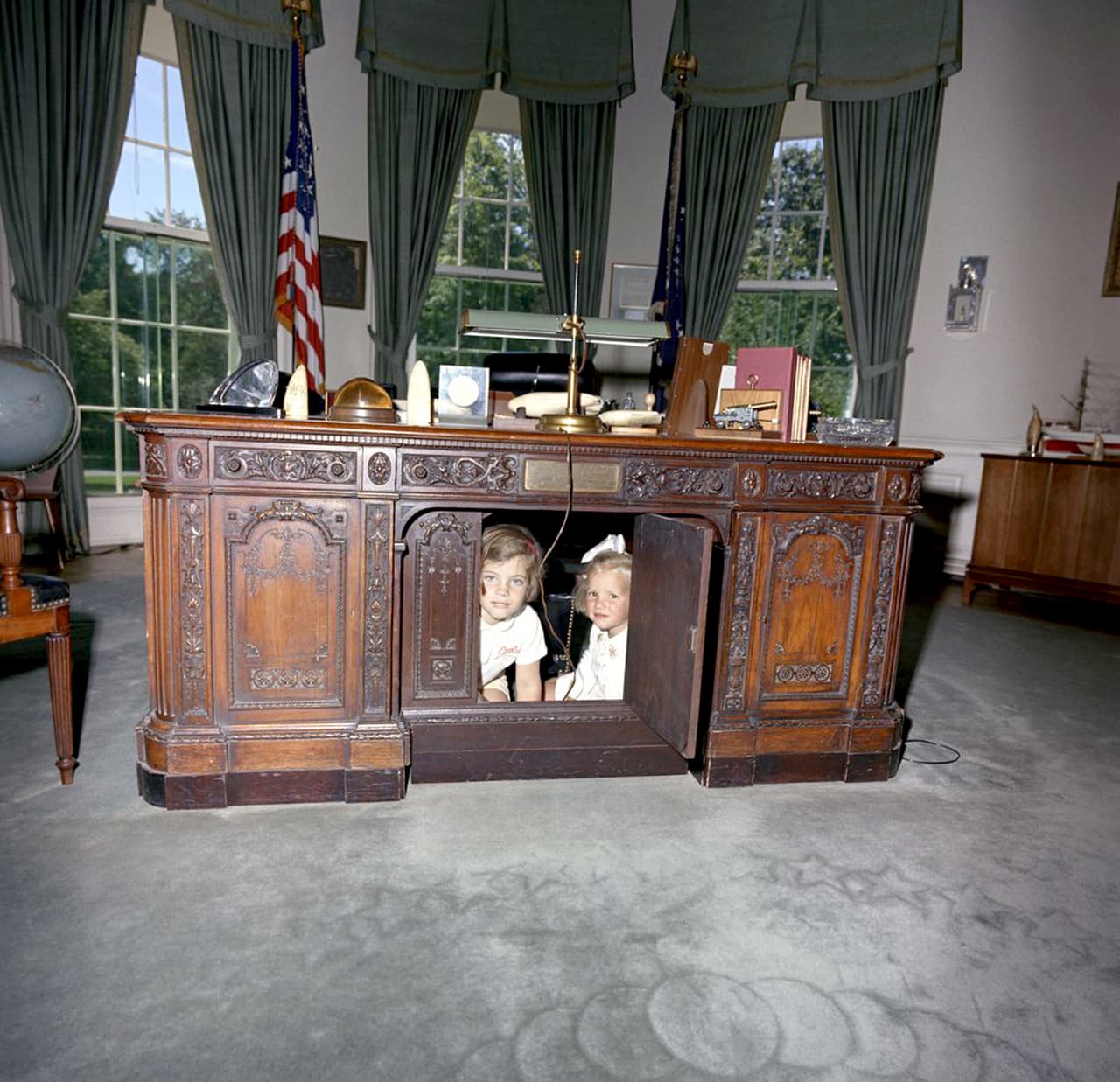 Caroline, hija del presidente John F. Kennedy, juega a esconderse con un amigo bajo el escritorio presidencial. 1963.
<br>