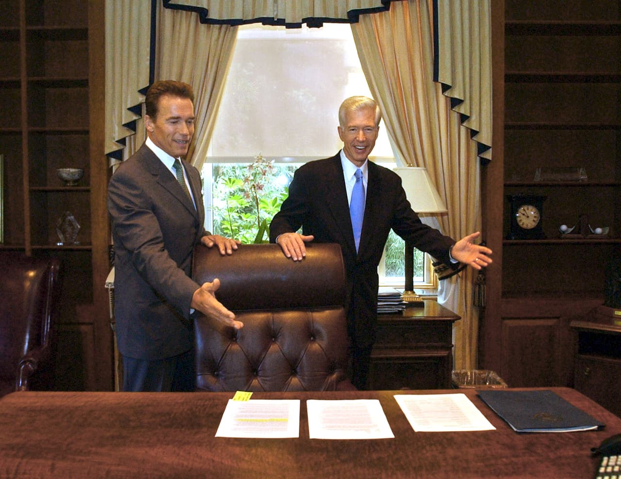 El derrotado Gray Davis muestra al gobernador electo Schwarzenegger el escritorio en Sacramento que ocuparía hasta 2011.
