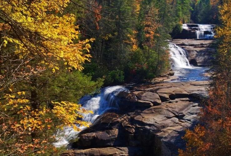 <b>High Falls y Triple Falls en Dupont State Park</b>. No muy lejos de la encantadora ciudad de Hendersonville, encontrarás el Parque Estatal Dupont y dos hermosas cascadas de fácil acceso a través de una ruta de senderismo. La primera cascada en el sendero es High Falls. Aquí es donde el Little River cae 150 pies por una larga pared rocosa. El mejor lugar para tomar una foto es desde el sendero directamente enfrente de la cascada o justo arriba en el gran refugio para picnic. Más adelante, llegarás a un sendero de entrada y salida que conduce a Triple Falls. Esta impresionante serie de cascadas es adecuadamente impresionante. Dependiendo del nivel del agua, se puede acceder a la base de High Falls y Triple Falls a través de senderos.