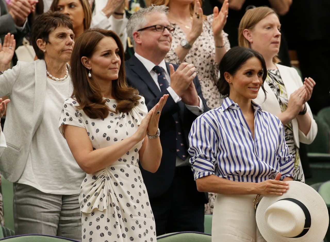 Meghan llevó un sombrero panamá blanco (mucho más caro que el que le habíamos visto en ocasiones) de la 
<a href="https://www.farfetch.com/shopping/women/maison-michel-natural-virginie-straw-hat-item-12967701.aspx?fsb=1&utm_content=[LinkTypeCode]&&ranSiteID=QFGLnEolOWg-CDtvw3vEopXHK0E194RrIw&utm_source=QFGLnEolOWg&utm_medium=affiliate&utm_campaign=Linkshareus&utm_content=15&utm_term=USNetwork&pid=rakuten_int&af_click_lookback=30d&clickid=QFGLnEolOWg-CDtvw3vEopXHK0E194RrIw&af_sub1=37508&af_siteid=QFGLnEolOWg&af_sub_siteid=444848&af_cost_model=CPA&af_channel=affiliate&is_retargeting=true">sombrerería francesa Maison Michel</a> en paja natural clara con cinta negra y sello de la marca ($675).