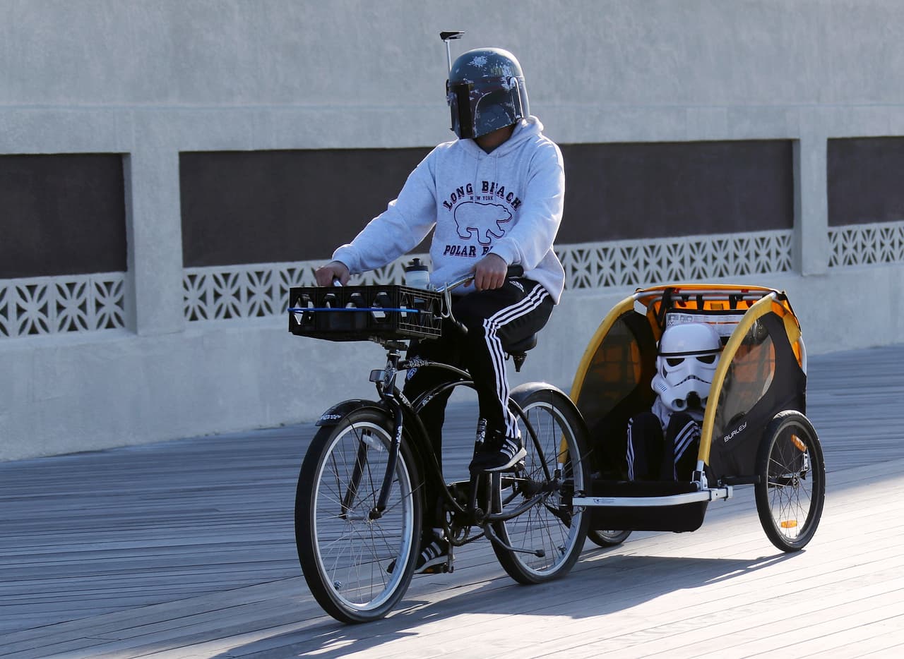 Un visitante pasea en su bicicleta en el paseo marítimo de Long Beach, Nueva York, con los cascos de los personajes de Star Wars, a pocas horas de su reapertura.