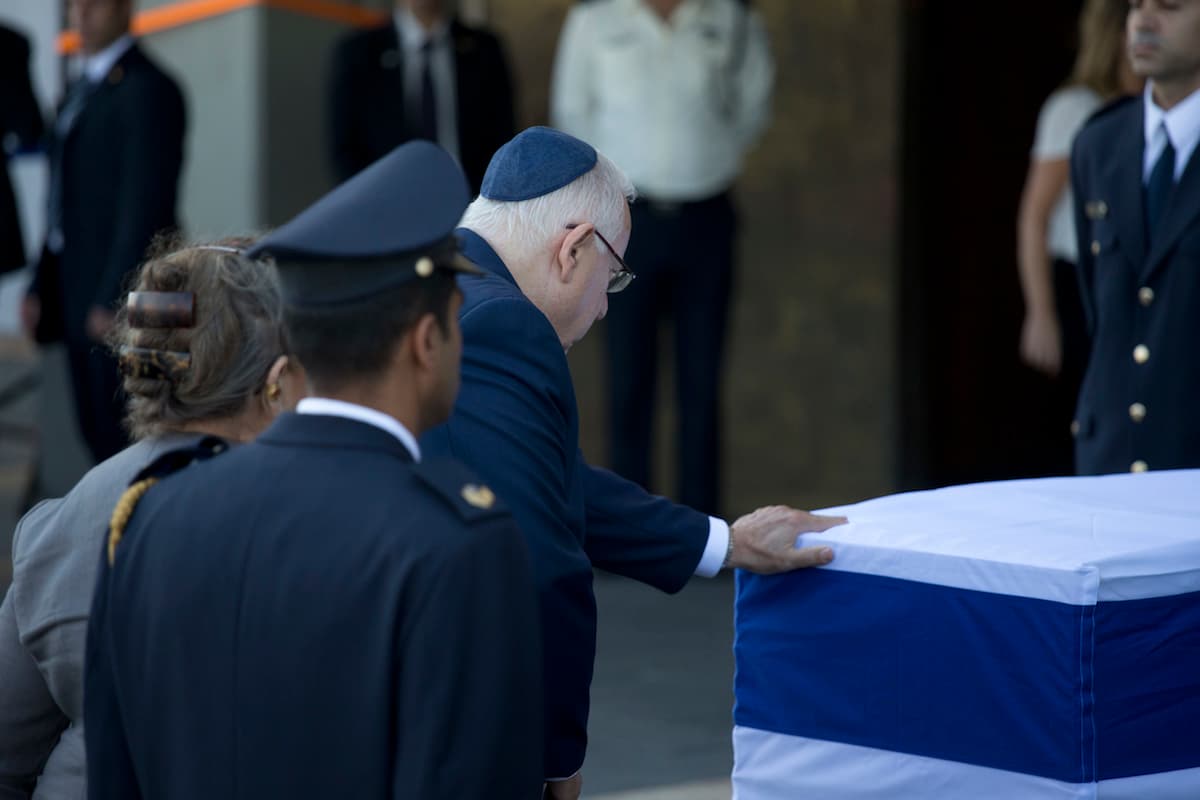 El presidente de Israel, Reuven Rivlin, toca el ataúd del expresidente Peres en la sede del parlamento