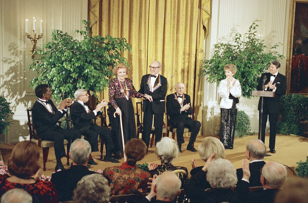 De izquierda a derecha: el coreógrafo Alvin Ailey, el actor y comediante 
<a href="https://es.wikipedia.org/wiki/George_Burns" target="_blank">George Burns</a>, la actriz 
<a href="https://es.wikipedia.org/wiki/Myrna_Loy" target="_blank">Myrna Loy</a>, el violinista 
<a href="https://en.wikipedia.org/wiki/Alexander_Schneider" target="_blank">Alexander Schneider</a>, el productor teatral, 
<a href="https://en.wikipedia.org/wiki/Roger_L._Stevens" target="_blank">Roger Stevens</a>: la primera dama 
<a href="https://www.univision.com/temas/nancy-reagan" target="_blank">Nancy Reagan</a> y el presidente 
<a href="https://www.univision.com/temas/ronald-reagan" target="_blank">Ronald Reagan</a> en la Casa Blanca el 4 de diciembre de 1988.