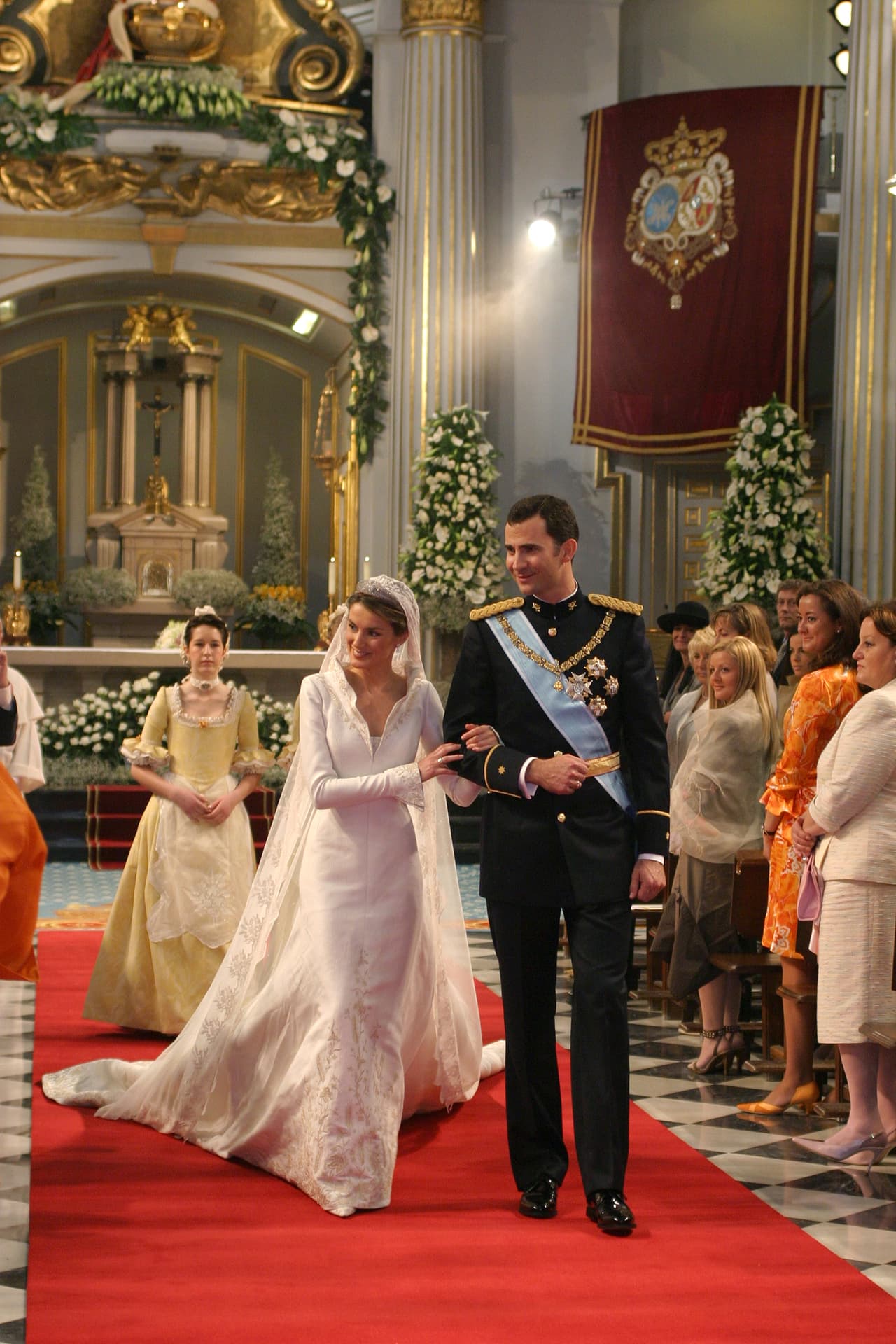 <b>2004 - Letizia Ortiz and Felipe, Prince of Asturias</b>
<br>The journalist wore a silk, princess-line gown, cut continuously from her shoulders to the floor, with golden heraldry embroidery and a rigid corolla collar by the talented Spaniard, Manuel Pertegaz. The veil was a personal gift from the groom.