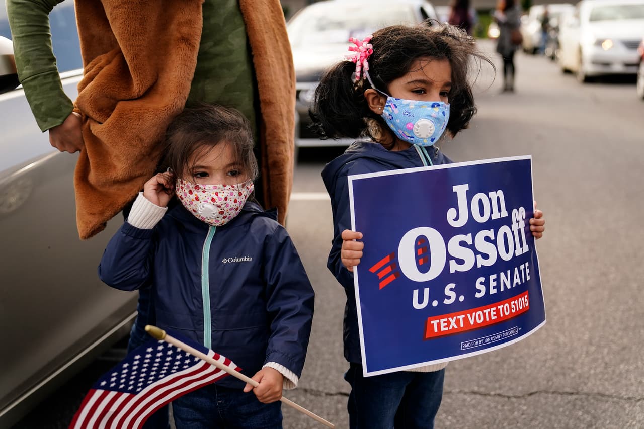 Un grupo de partidarios, incluyendo estas dos niñas, esperan para escuchar a los candidatos demócratas al senado Jon Ossoff y Raphael Warnock durante un evento de campaña el domingo 15 de noviembre en Marietta, Georgia.