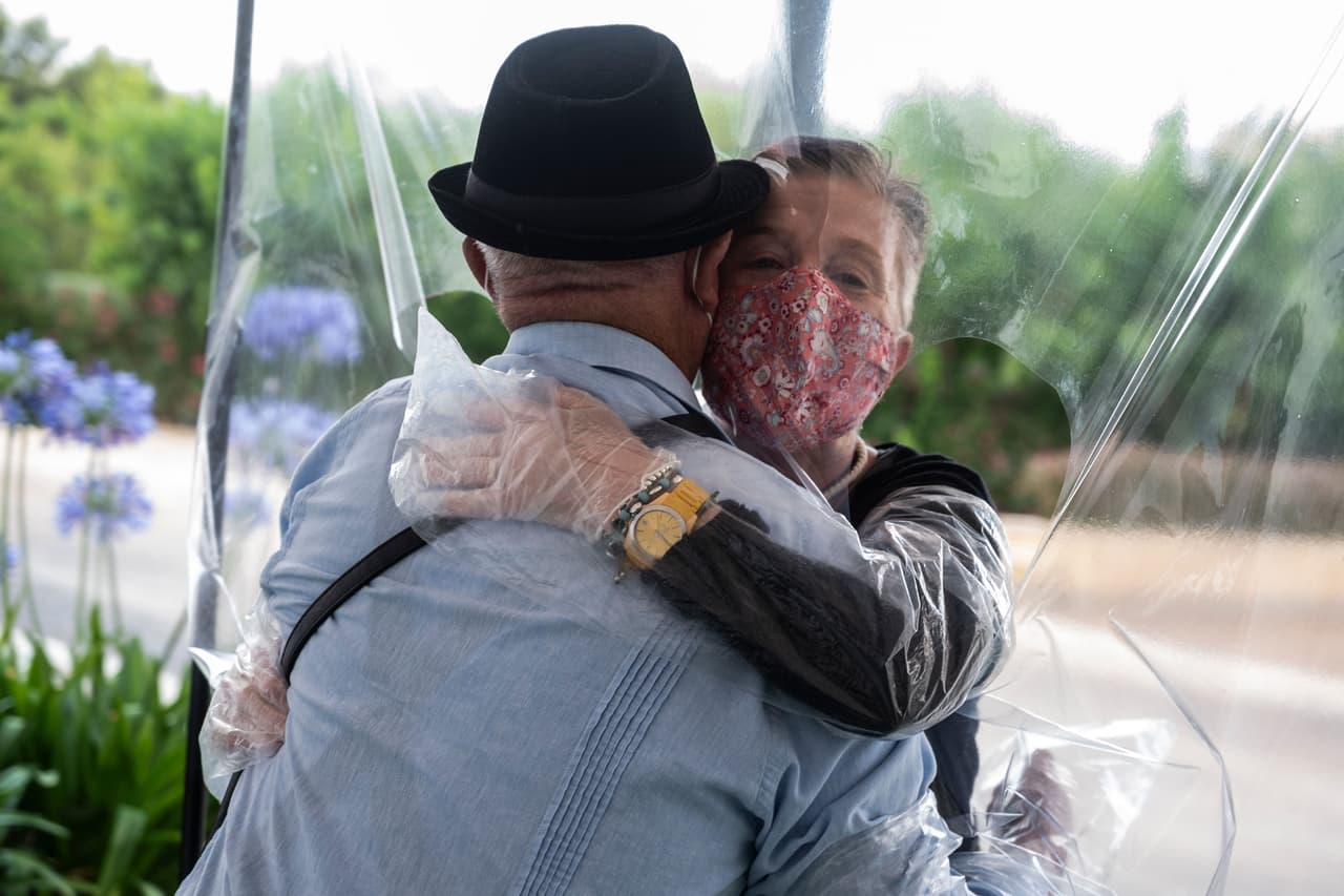 Una mujer abraza -a través del plástico- a su padre con manos, brazos, boca y nariz cubierta, para protegerlos de algún posible contagio, al reanudarse las visitas en la ciudad de Valencia. 
<br>
<br>Tras estas emocionantes interacciones, las visitas duran aproximadamente 30 minutos con una distancia de dos metros entre cada persona.