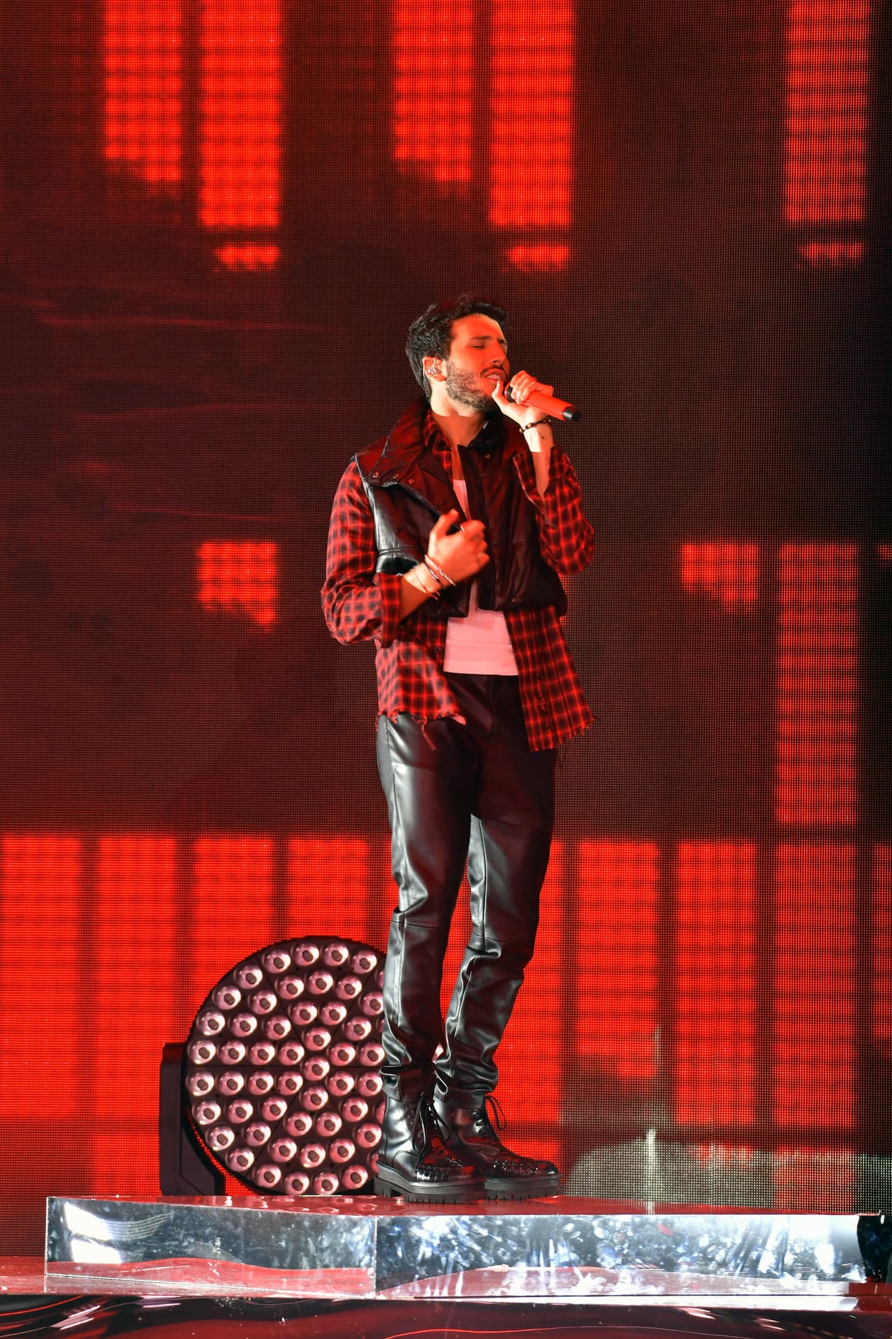Pero ya en el show cambió la parte de arriba de su vestuario y apareció con un pequeño chaleco negro, camisa de cuadros y una camiseta blanca.