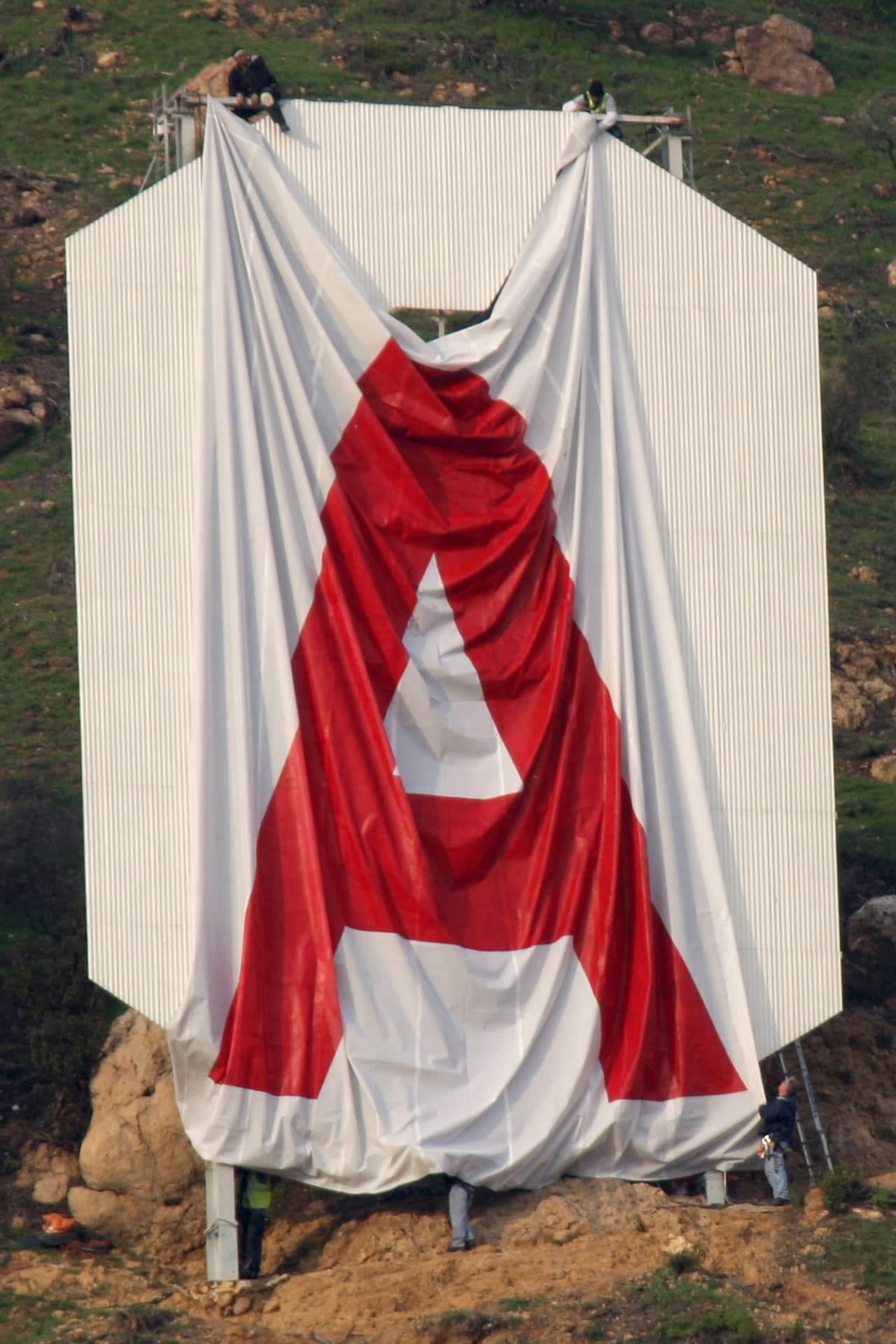 Unos activistas despliegan una lona con la letra 'A' para cubrir una de las letras 'O' del letrero de Hollywood el 11 de febrero de 2010. Cada una de las letras mide 45 pies.