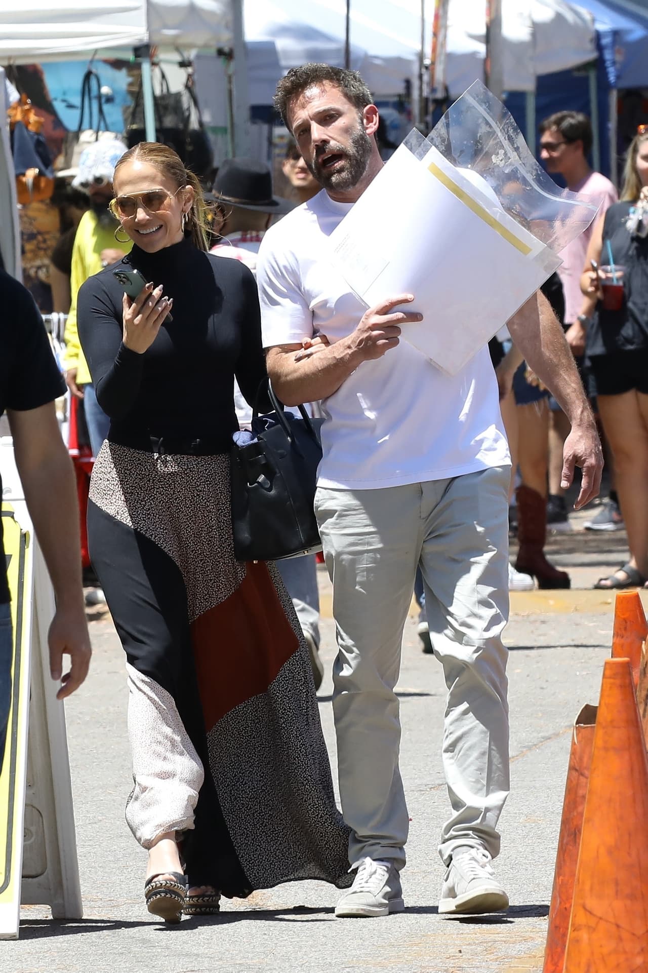 A JLo se le captó sosteniendo su teléfono celular mientras caminaba por el mercado del brazo de su futuro marido. 
<br>