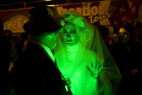 Una mujer simulando ser la Catrina intenta llamar la atención de este hombre en el tradicional desfile de Día de Muertos en Guadalajara.  