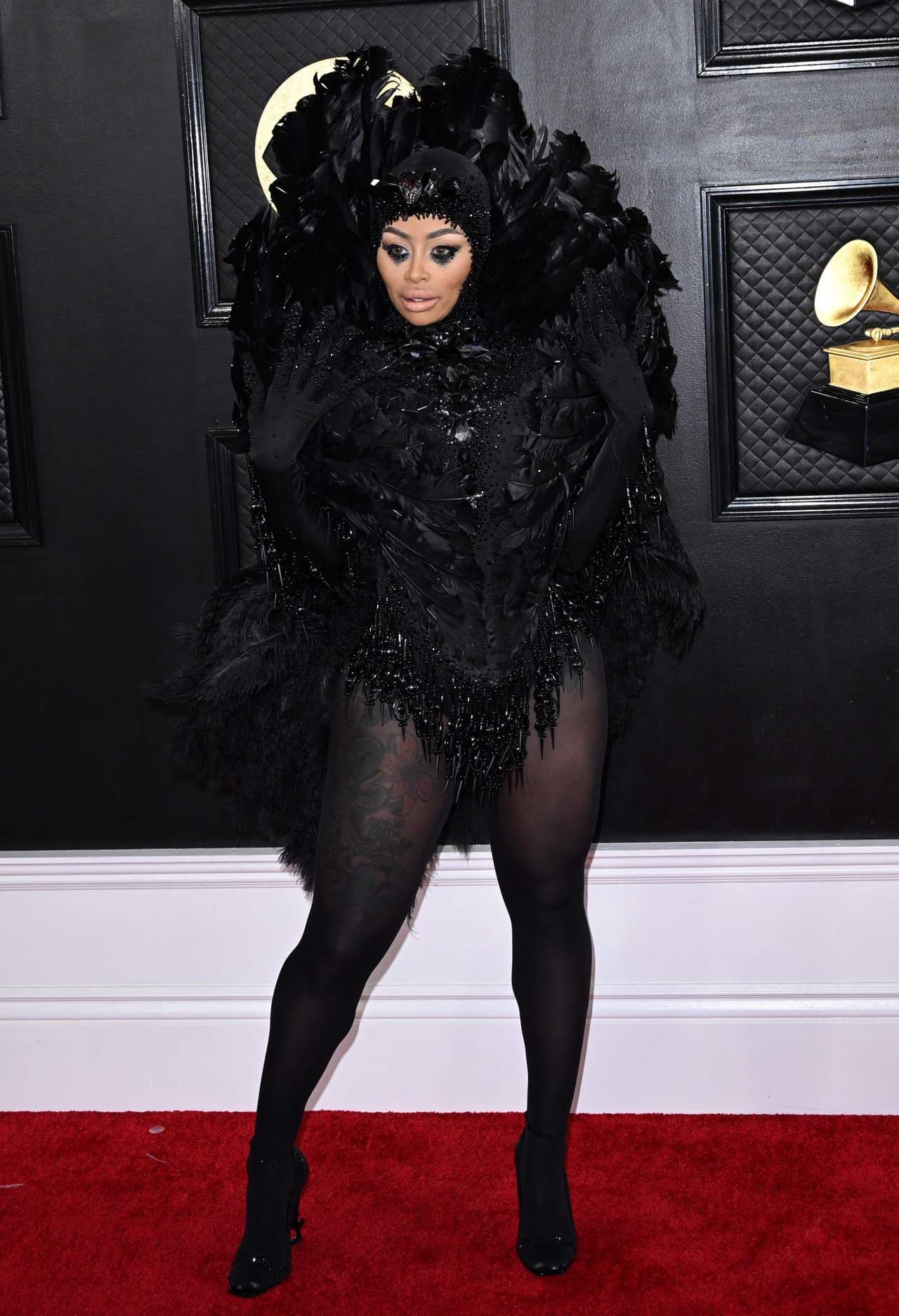<h2 class="cms-H2-H2">Blac Chyna</h2>
<br>Envuelta en plumas negras, la modelo enamoró a las cámaras en la alfombra roja. Su outfit estuvo conformado por zapatillas, medias y guantes negros, así como un corset del mismo color.