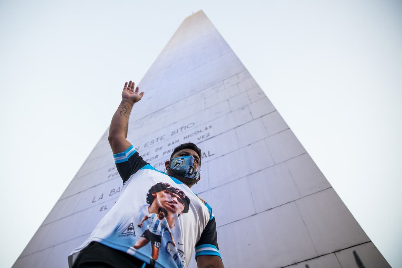 En los pies del Obelisco en Buenos Aires, un fanático con una camiseta con la imagen de Maradona alza su brazo derecho para despedir al exentrenador de la Sección Argentina de Fútbol. 
<br>