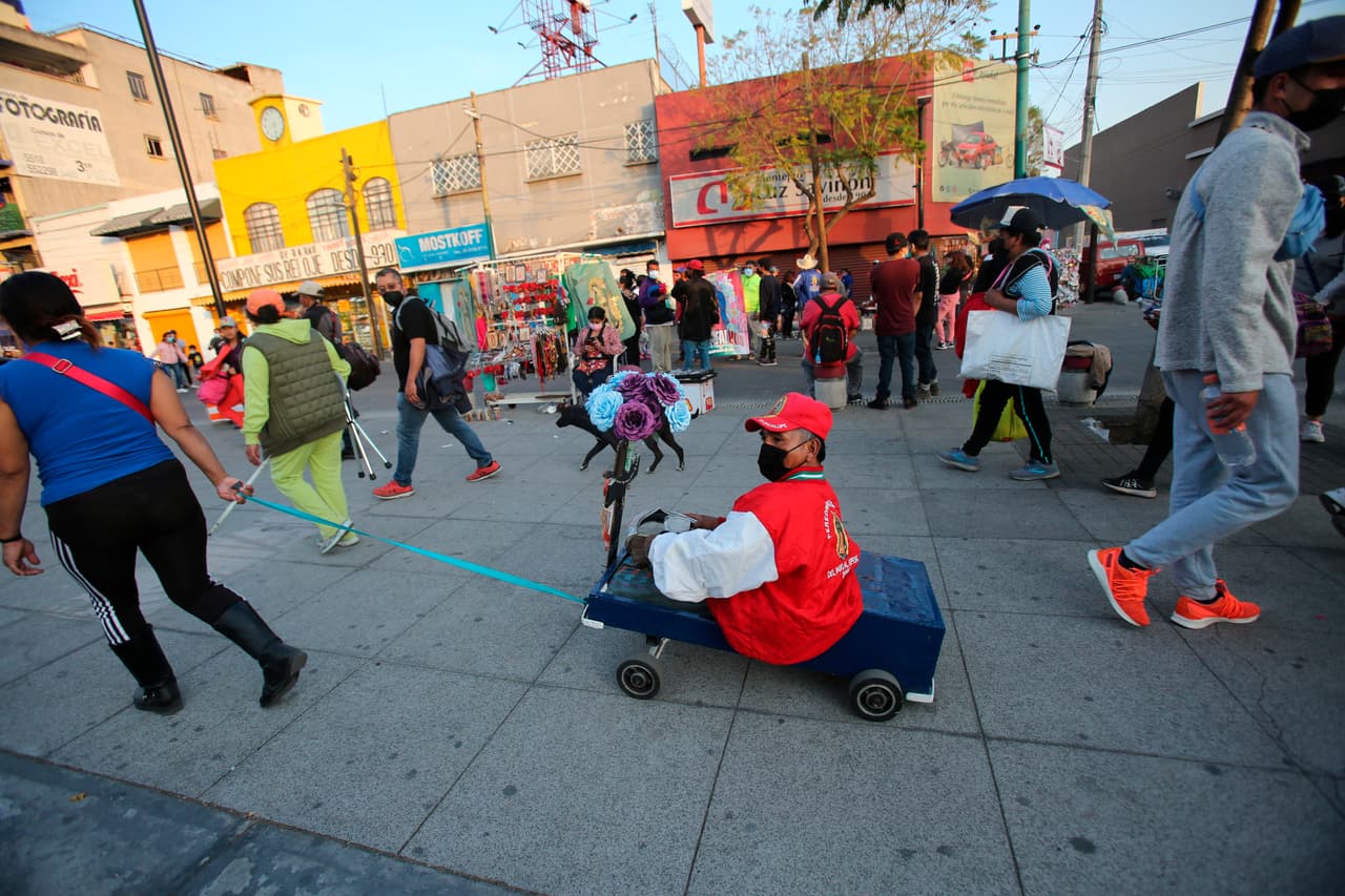 Manuel Rojas Perez, de 48 años, quien sufrió poliomelitis, es transportado por su esposa, Guadalupe Martínez, mientras se dirige a la Basílica guadalupana.