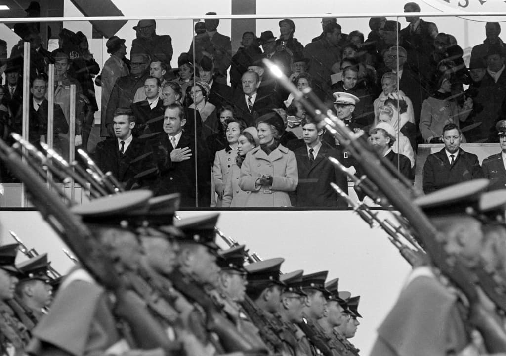 ARCHIVO - El presidente Nixon saluda mientras los cadetes de la Academia Militar de West Point pasan por la tribuna presidencial durante el desfile inaugural en Washington, D.C., el 20 de enero de 1969. En la primera fila de la tribuna, de izquierda a derecha, están Doug Rogers, el presidente, Barbara Eisenhower, Julie Nixon Eisenhower, Pat Nixon, David Eisenhower y Mamie Eisenhower. (Foto AP, Archivo)