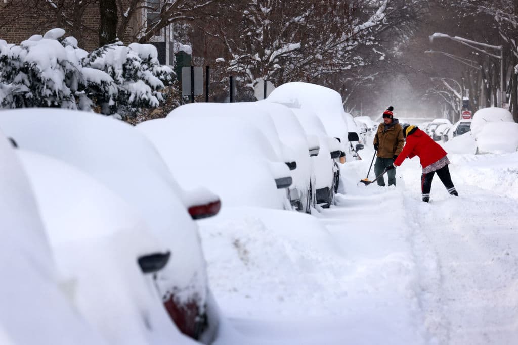 La gente trabaja para excavar la nieve y poder retirar su automóvil en una calle residencial el 16 de febrero de 2021 en Chicago, Illinois.