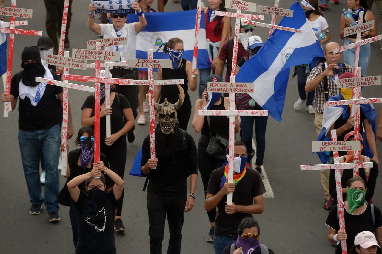 Un grupo de manifestantes con cruces ensangrentadas con algunos de los derechos que consideran que Ortega los ha usurpado.