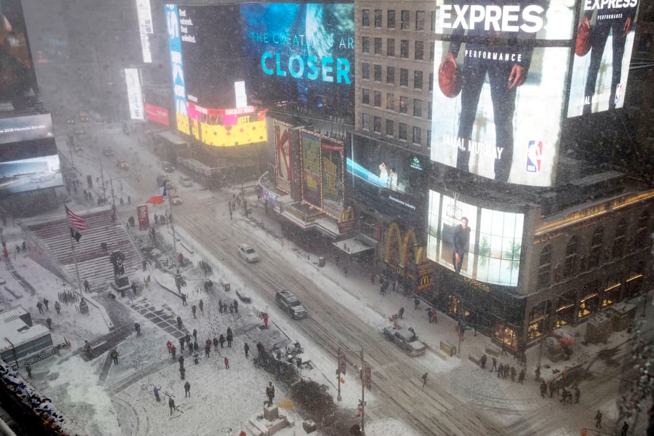 Los autos circulan por concurrida zona de Times Square en Nueva York, luego que las máquinas palearon la nieve de las vías.