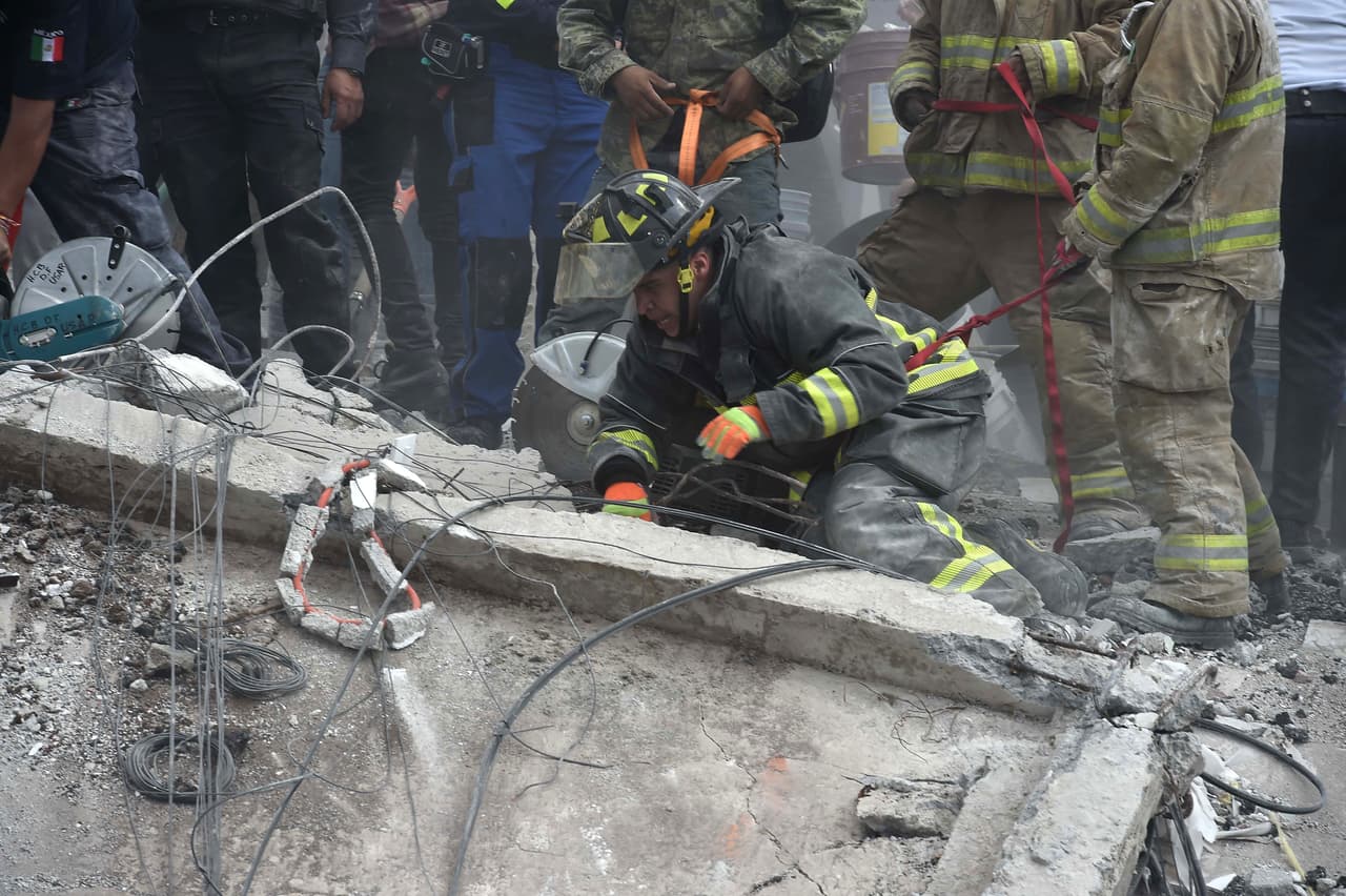 Un bombero explora en los escombros en busca de un sobreviviente del sismo.