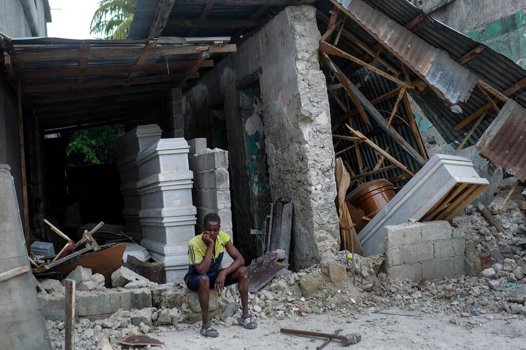 Un hombre se sienta frente a los escombros de una funeraria, en Les Cayes, Haití.