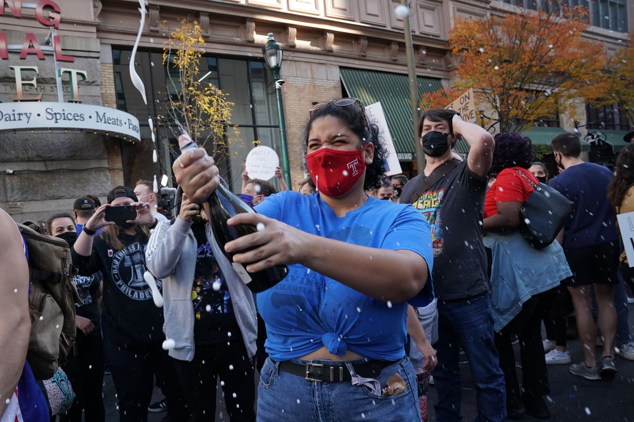Raven Smith rocía a la multitud en celebración fuera del Centro de Convenciones de Pensilvania después de que Joe Biden fuera declarado ganador de las elecciones presidenciales de 2020 el 7 de noviembre de 2020 en Filadelfia, Pensilvania.