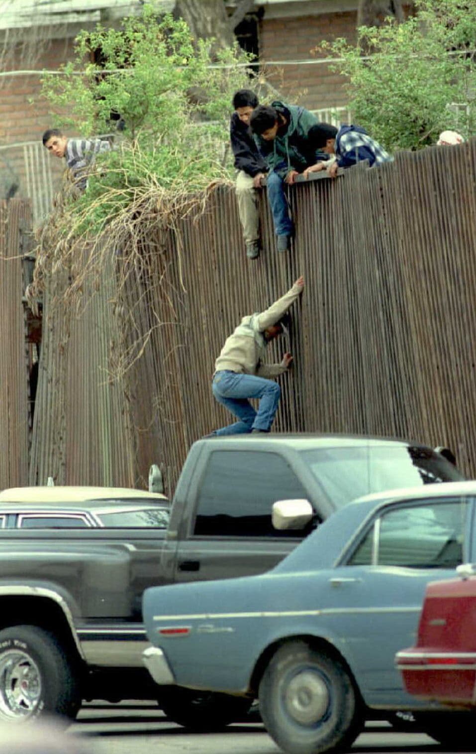 En esta imagen, de febrero de 1995, migrantes saltan sobre la barda que separa a México de Estados Unidos en el centro de Nogales, Arizona. La barrera, que fue llamada por algunos “El Muro de la Tortilla”, provocó en poco tiempo un cambio en el flujo migratorio a través de la zona de San Diego. Las rutas utilizadas para cruzar la frontera se desviaron hacia las montañas al este y a los desiertos del sur de Arizona.