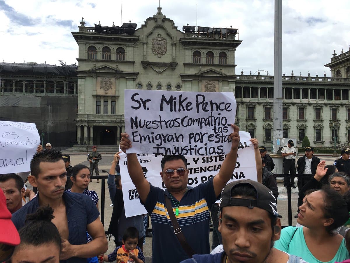 Protester Manuel Maldonado, 35, outside the presidential palace in Guatemala City with a sign that reads: "Mr Mike Pence, our couontrymen emigrate for these injustices," referring to low police pay. June 28, 2018.