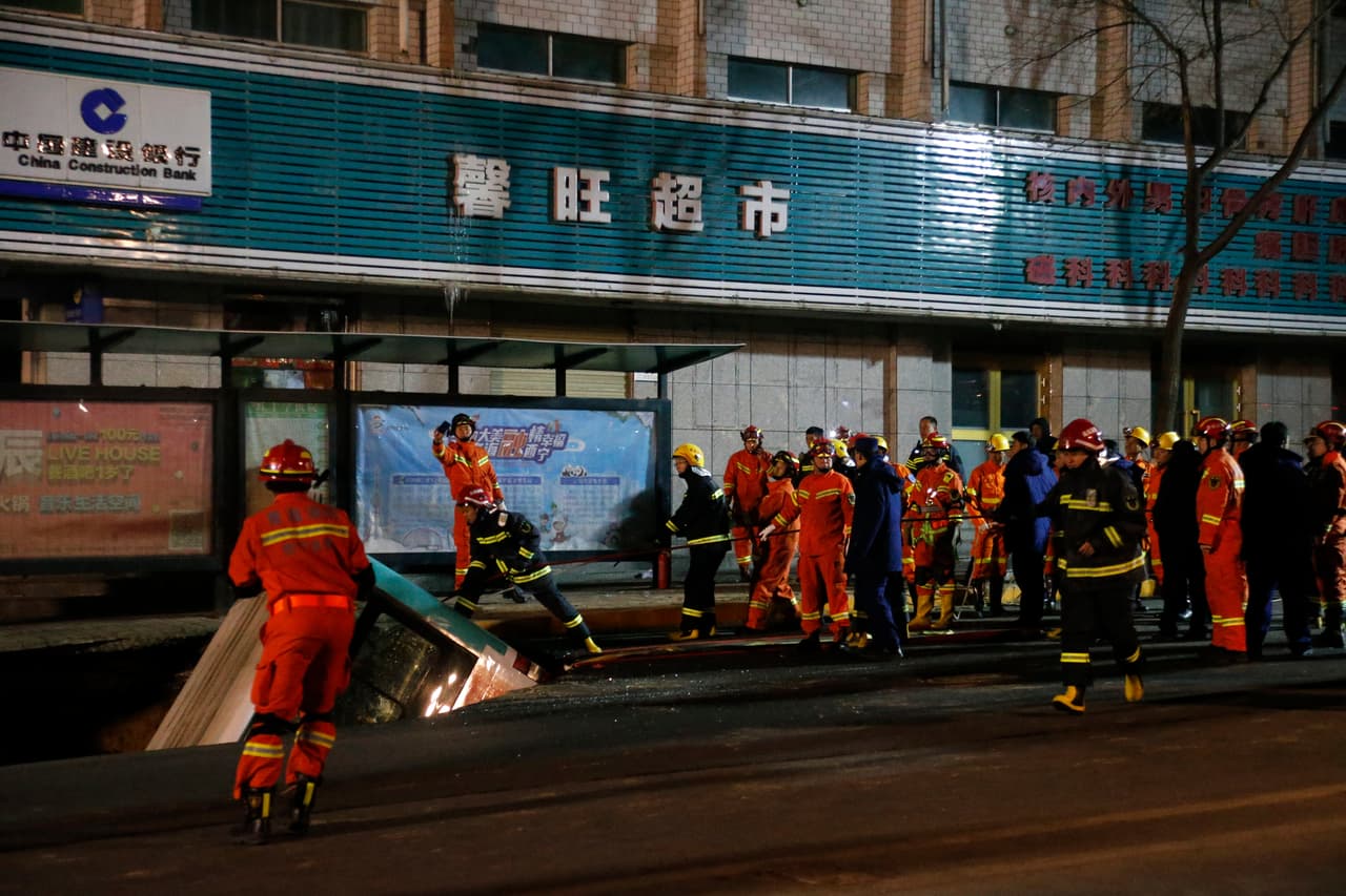 Elementos de rescate laborar para sacar el camión que cayó dentro de un socavón en China