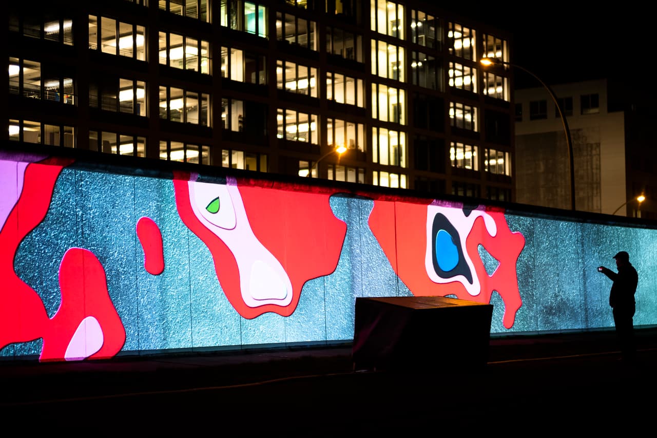 Algunas partes de la barrera se han conservado, como la galería del lado este (en la fotografía), una porción de casi una milla de muro donde se exponen obras de arte sobre acontecimientos relacionados con los años de división. Esta fotografía fue tomada el 4 de noviembre de 2019 en una proyección multimedia sobre el muro, parte de los actos conmemorativos a 30 años de su caída.