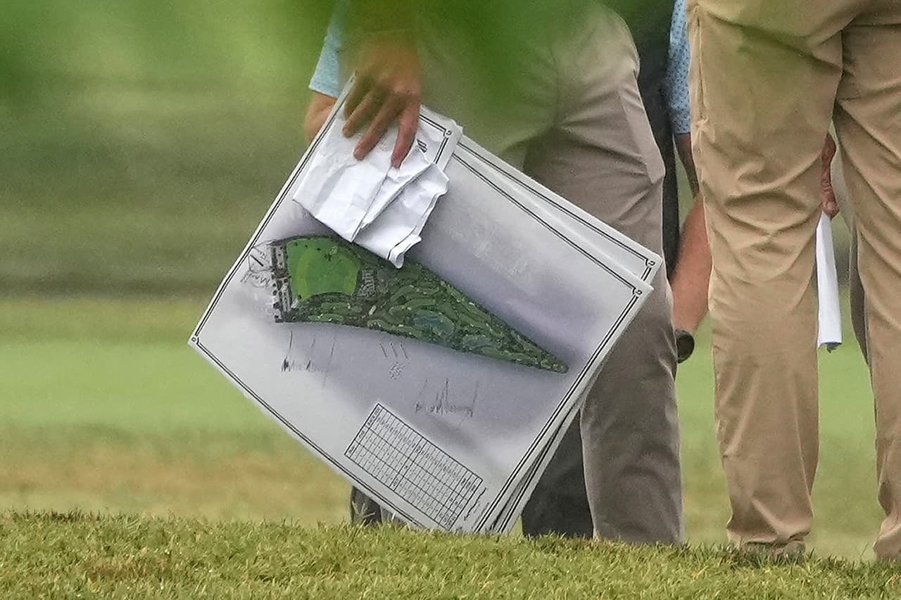 Una persona lleva planos mientras el presidente Donald Trump recorre el campo de golf de East Potomac Park.