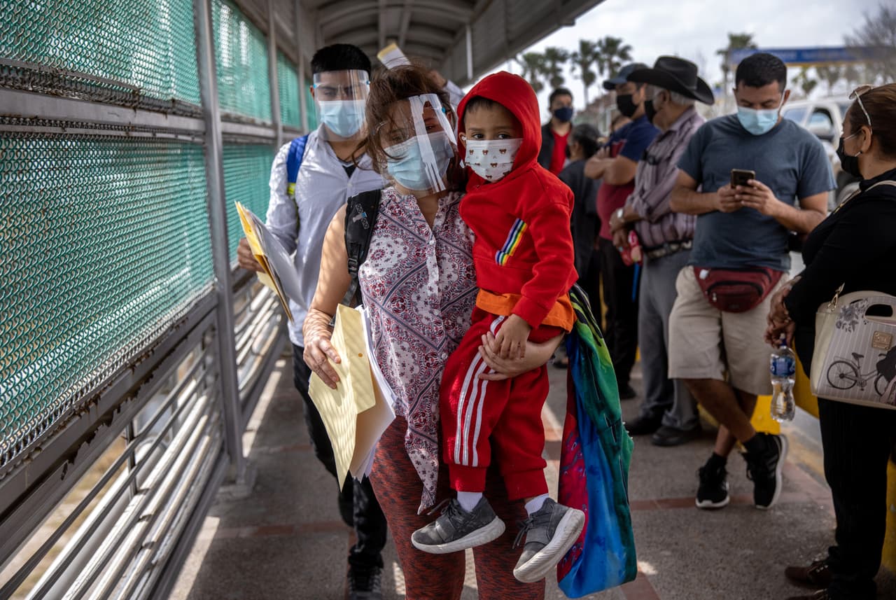<b>Un nuevo comienzo. </b>Una madre hondureña lleva a su hijo, de 4 años, a través de la frontera entre Estados Unidos y México como parte de un grupo de al menos 25 solicitantes de asilo a quienes se les permitió viajar desde un campamento de migrantes en México a los Estados Unidos el 25 de febrero de 2021 en Matamoros, México.