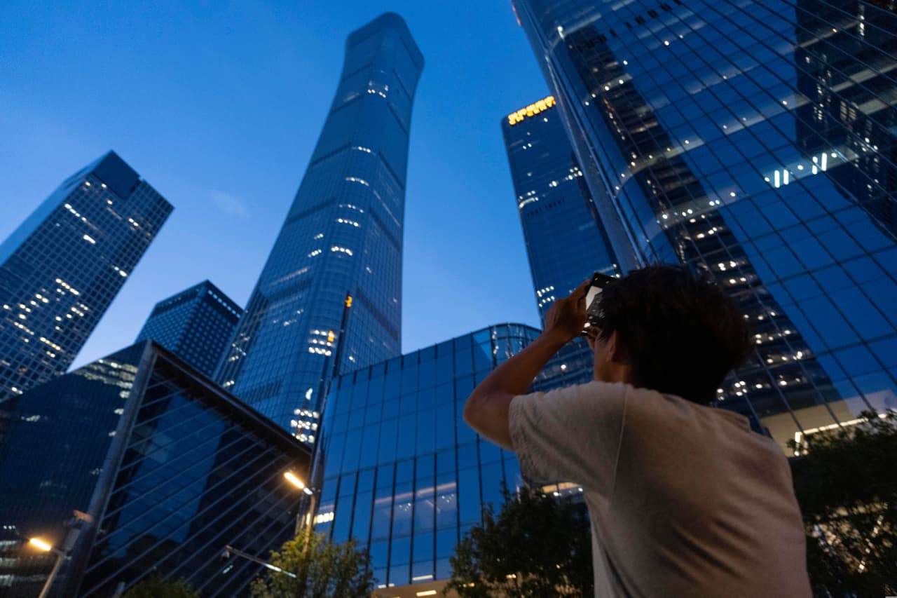 Un transeúnte intenta fotografiar los daños en la Torre Citic, también conocida como Torre Zun, en Pekín, China, el viernes 26 de junio de 2026.