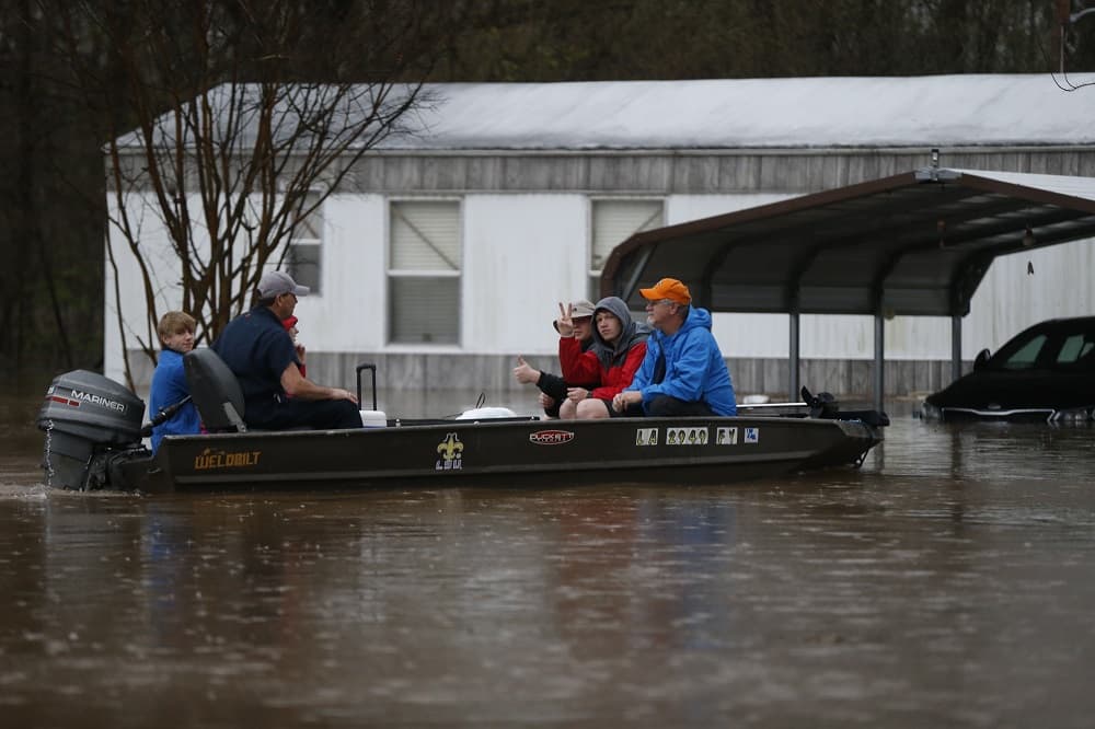 Varias personas utilizan una lancha con motor para poder abandonar sus casas tras las fuertes inundaciones.