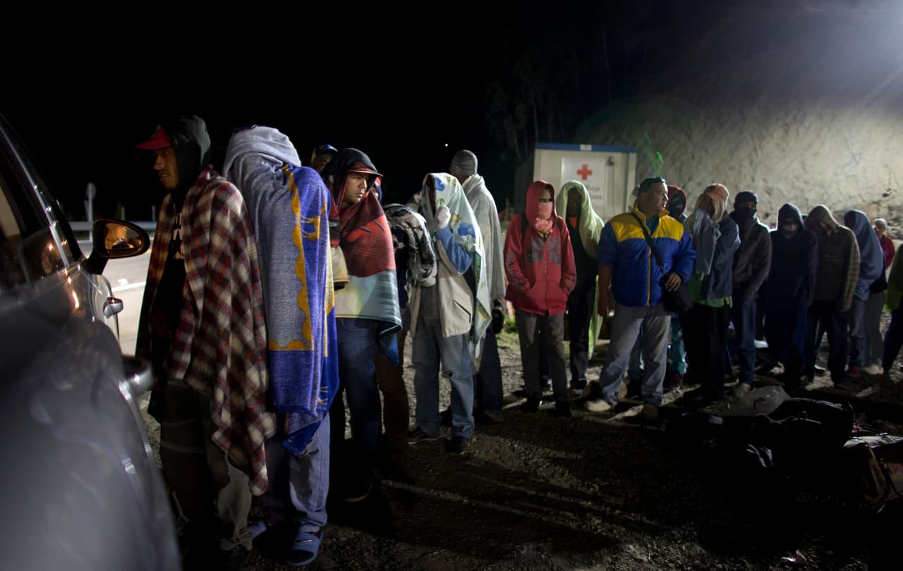Migrantes venezolanos hacen fila para recibir el pan y café que reparte una familia colombiana desde su auto, en una gasolinera en Pamplona, Colombia. Carlos Valdés, director del Instituto Nacional Forense de Colombia, cree que la hipotermia ha matado a algunas personas en la región montañosa, pero no tiene idea de cuántas. Esta imagen fue tomada el 31 de agosto de 2018. (AP Foto/Ariana Cubillos, archivo)