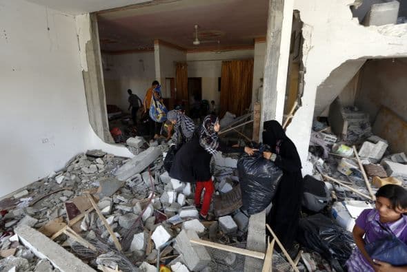 Mujeres palestinas encuentran en ruinas su casa, al norte de Gaza.