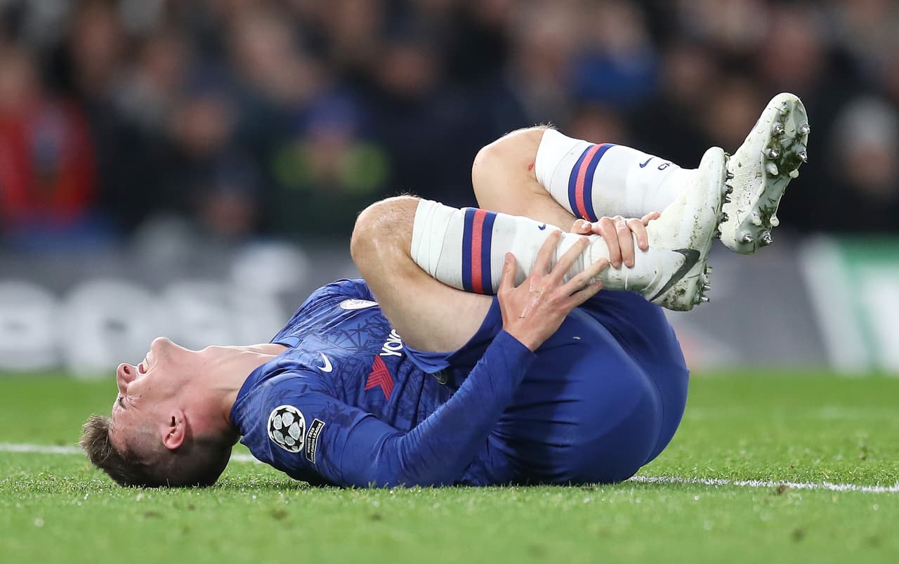 Mason Mount del Chelsea se lamenta en el pasto tras entrada fuerte.