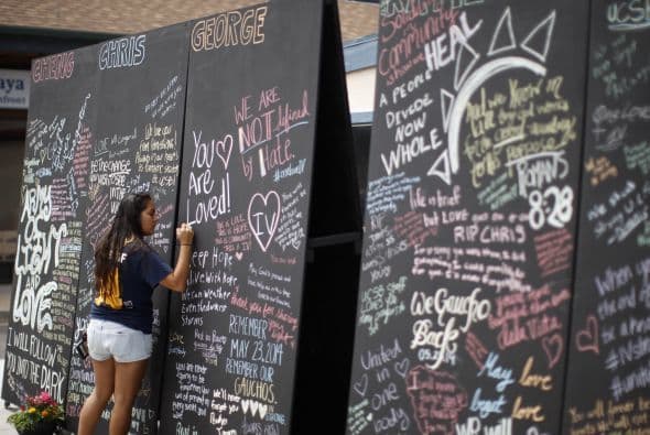 Un estudiante escribe mensajes con tiza en una pared en memoria de los estudiantes muertos.