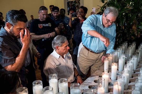 El gobernador de Texas, Greg Abbott, y el alcalde de El Paso, Dee Margo, encienden velas después de una vigilia en la Iglesia de San Pío X.