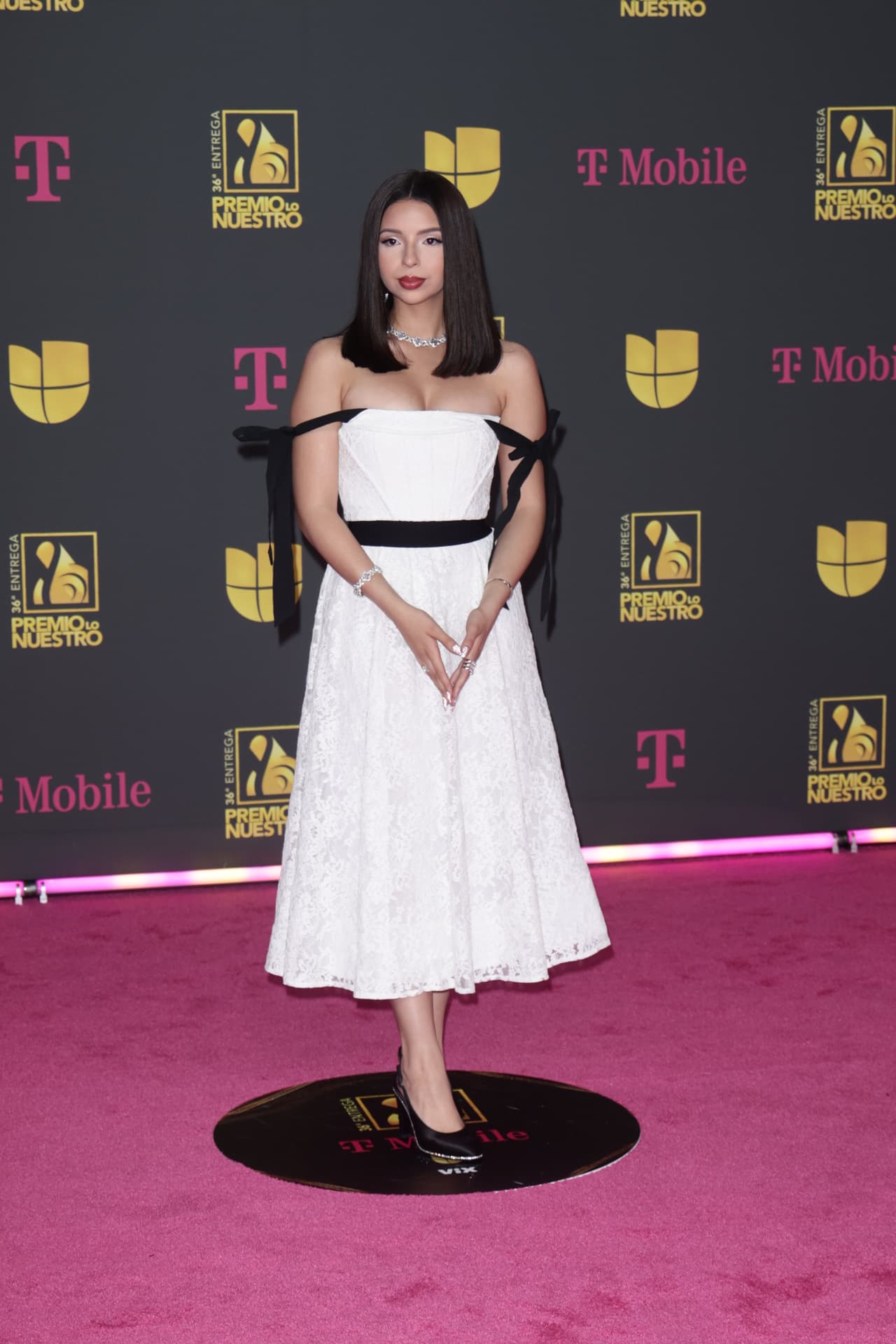 <b>Ángela Aguilar</b>
<br>
<br>La joven cantante le dio un toque sobrio y clásico a su estilo y en su paso por la alfombra magenta de Premio Lo Nuestro 2024 lució un vestido blanco con detalles en negro.