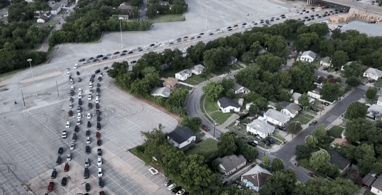 Se forman largas filas de vehículos durante la distribución de alimentos en el parque de la feria en Dallas
