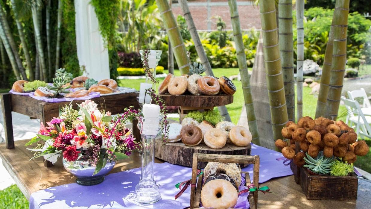 Las donas se abren paso entre los 
<i>cup-cakes</i> y los 
<i>macarons</i> que se convirtieron en un 
<i>‘wedding must’</i> hace un par de años. Puedes tener una 
<i>donut bar</i> en vez del pastel —o además de él—, con variedad de sabores para elegir o acompañarlas de 
<i>toppings</i> para que puedan ser personalizadas.