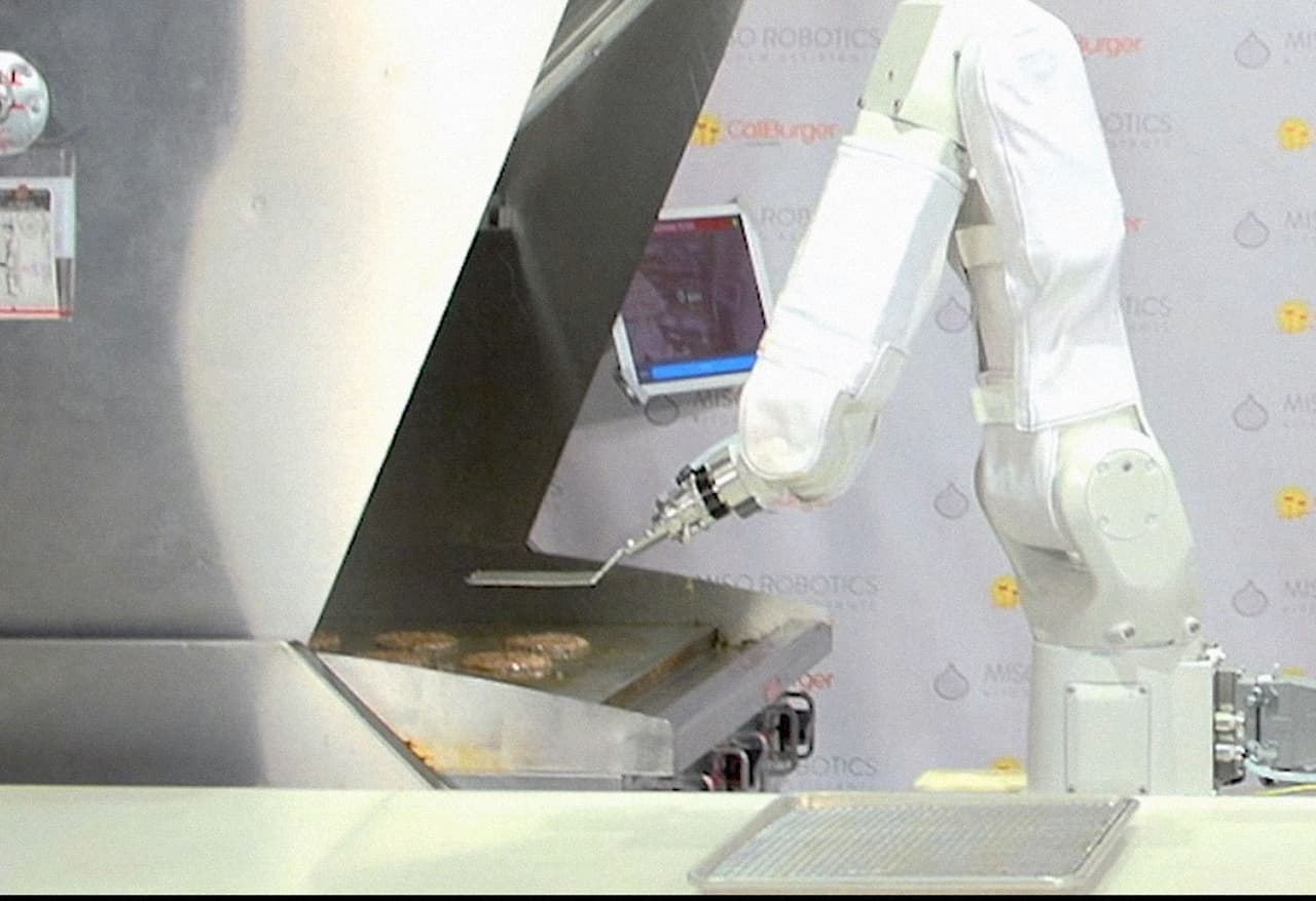 Gracias a un escáner 3D, la máquina puede ‘ver’ y hacer los cálculos para colocar la carne sobre la plancha y, cuando es necesario, les da vuelta con un movimiento rápido y preciso. Después, las coloca sobre la base inferior de un pan y enseguida una cocinera humana coloca el resto de los ingredientes elegidos por el comensal.